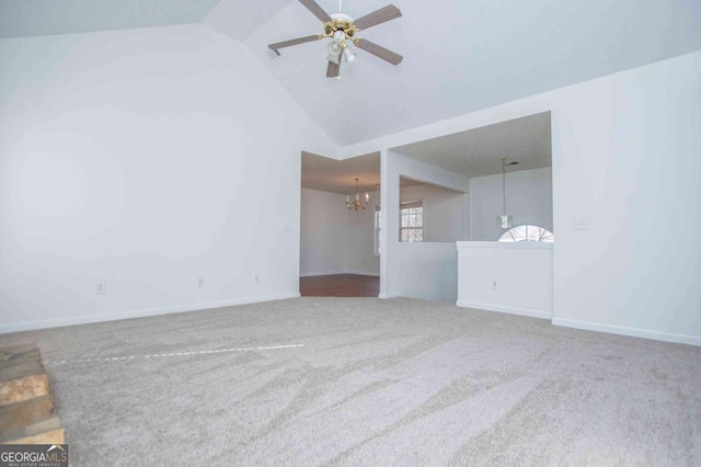 unfurnished living room with ceiling fan with notable chandelier, carpet floors, high vaulted ceiling, and baseboards