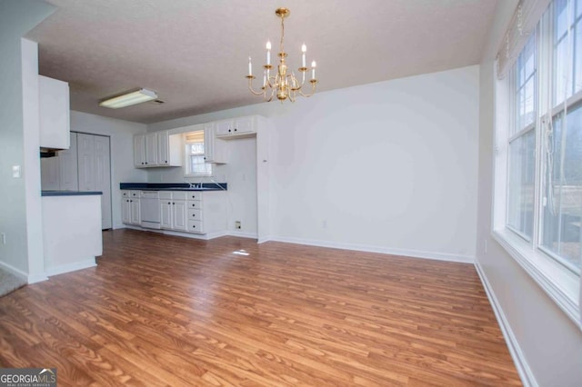 interior space featuring a chandelier, a textured ceiling, baseboards, and wood finished floors