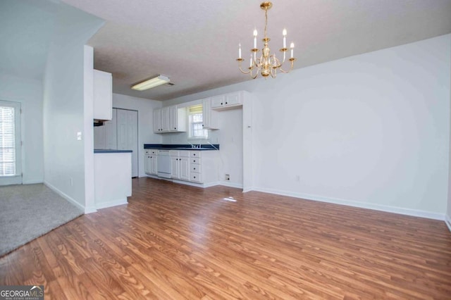 unfurnished living room featuring light wood-style floors, baseboards, and an inviting chandelier