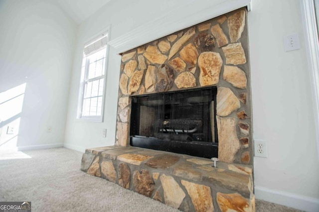 room details featuring baseboards, carpet flooring, and a stone fireplace