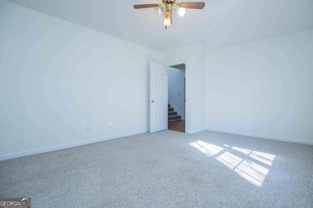 carpeted empty room with ceiling fan and baseboards