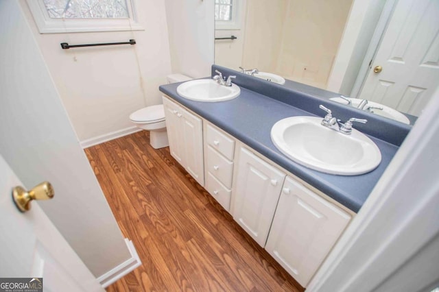 bathroom with double vanity, a sink, toilet, and wood finished floors