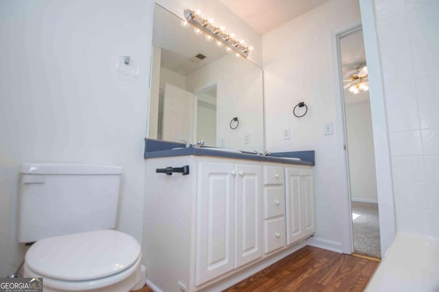 bathroom with ceiling fan, toilet, wood finished floors, visible vents, and vanity