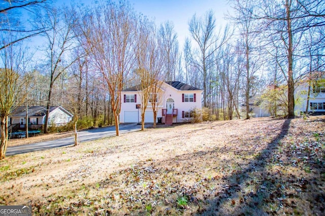 view of front of home with a garage, driveway, and a trampoline