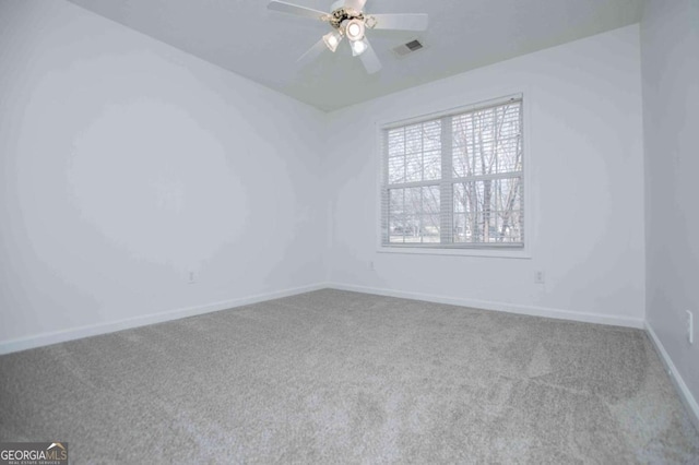 carpeted empty room with baseboards, visible vents, and a ceiling fan