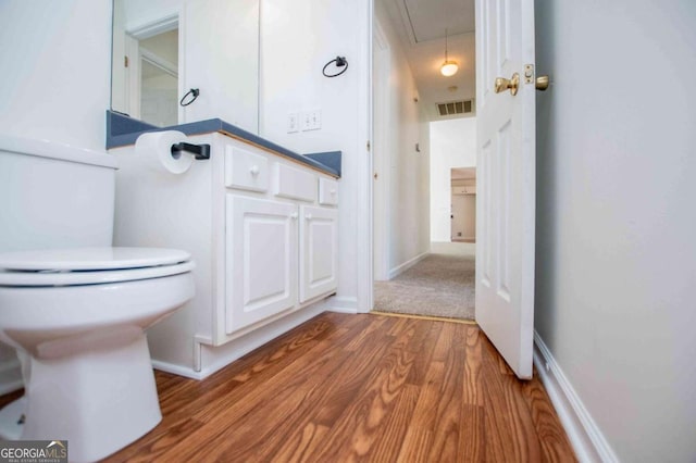 bathroom with toilet, baseboards, visible vents, and wood finished floors