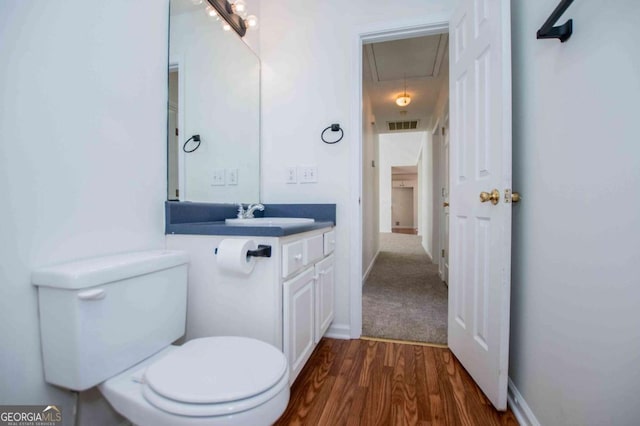 bathroom featuring baseboards, visible vents, toilet, wood finished floors, and vanity