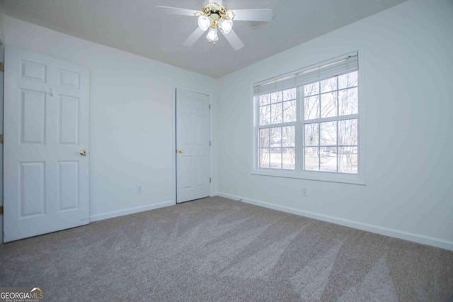 unfurnished room featuring carpet floors, ceiling fan, and baseboards