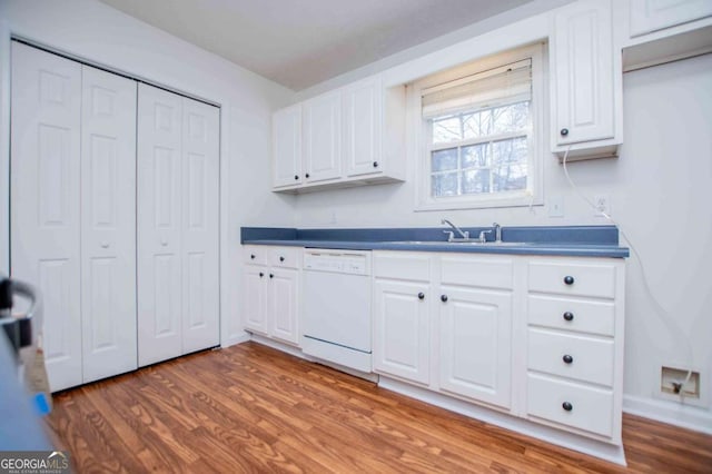 kitchen with dishwasher, wood finished floors, a sink, and white cabinetry