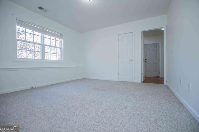 unfurnished room with carpet floors, visible vents, and baseboards