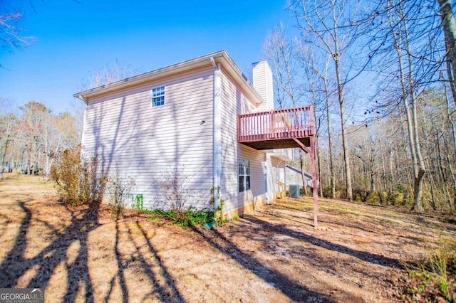 view of side of property featuring a deck, central AC, and a chimney