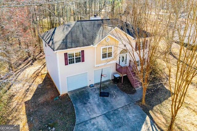 view of front of home featuring concrete driveway, a chimney, and an attached garage