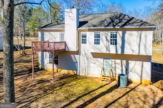 rear view of property featuring entry steps, a deck, central AC, a yard, and a chimney