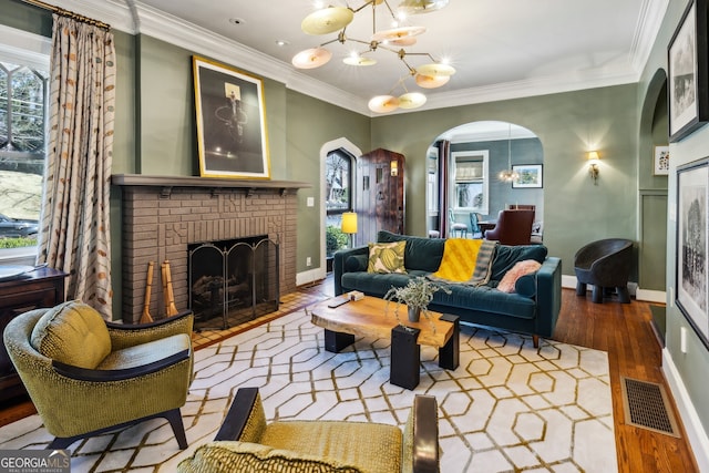 living room featuring arched walkways, ornamental molding, visible vents, and an inviting chandelier