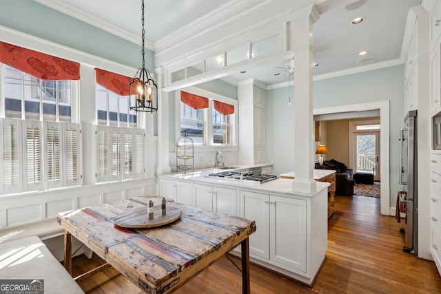 kitchen featuring ornate columns, crown molding, a peninsula, and gas stovetop