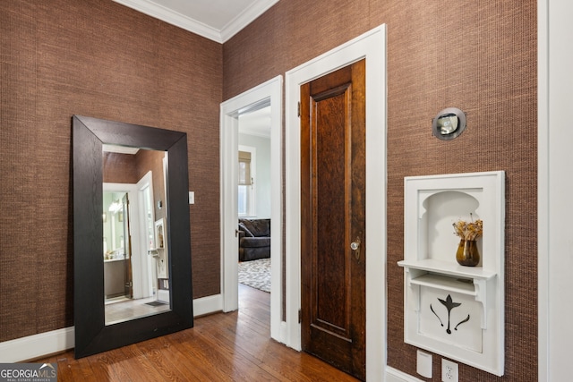 corridor featuring ornamental molding, wallpapered walls, baseboards, and hardwood / wood-style flooring