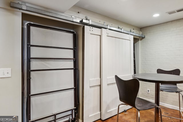 interior space featuring brick wall, a barn door, and visible vents