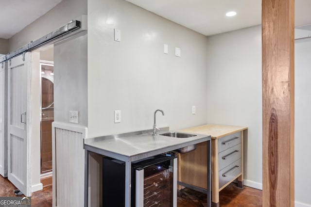 kitchen with a barn door, beverage cooler, stainless steel counters, a sink, and recessed lighting