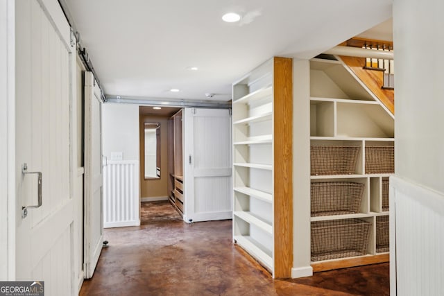 hallway with concrete flooring, recessed lighting, stairs, and a barn door