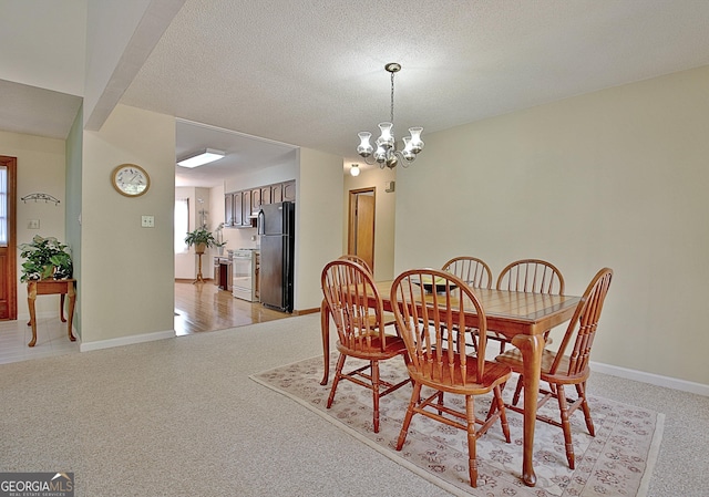 dining space featuring light carpet, a textured ceiling, baseboards, and a notable chandelier