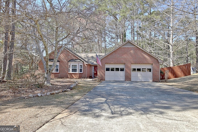 single story home featuring brick siding, an attached garage, fence, and aphalt driveway