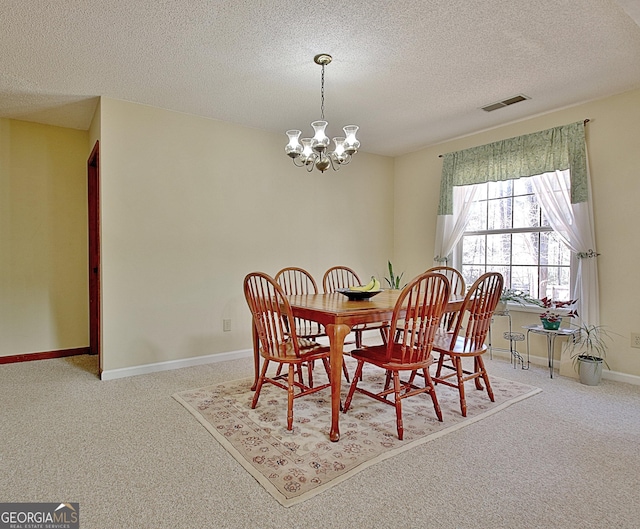 carpeted dining area with baseboards, a textured ceiling, visible vents, and an inviting chandelier