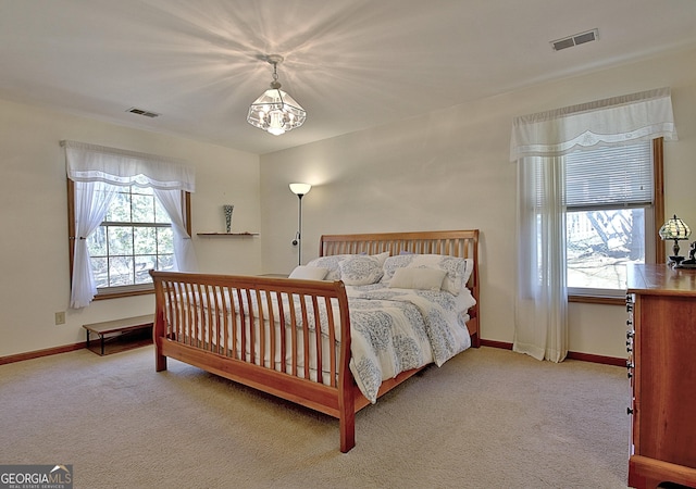 carpeted bedroom with an inviting chandelier, visible vents, and baseboards