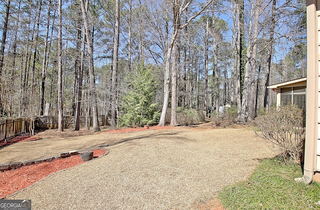 view of yard featuring driveway, fence, and a sunroom