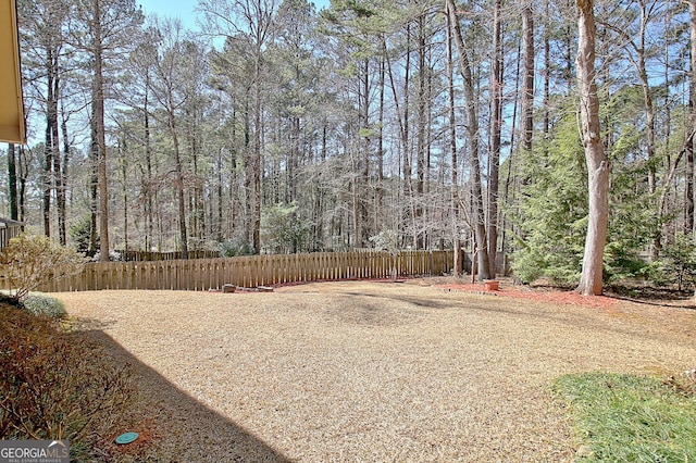 view of yard featuring a forest view and fence