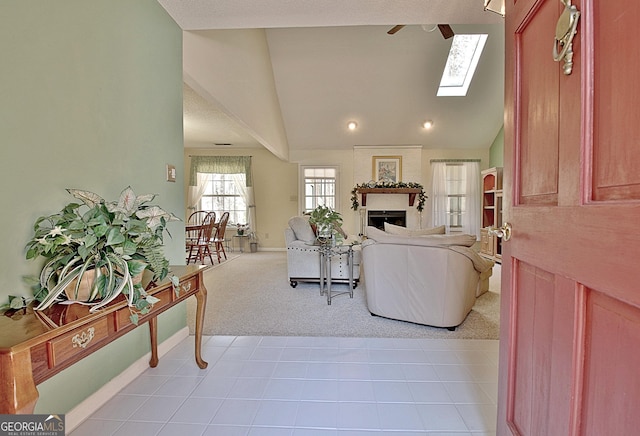 living area with lofted ceiling with skylight, light colored carpet, a fireplace, and baseboards