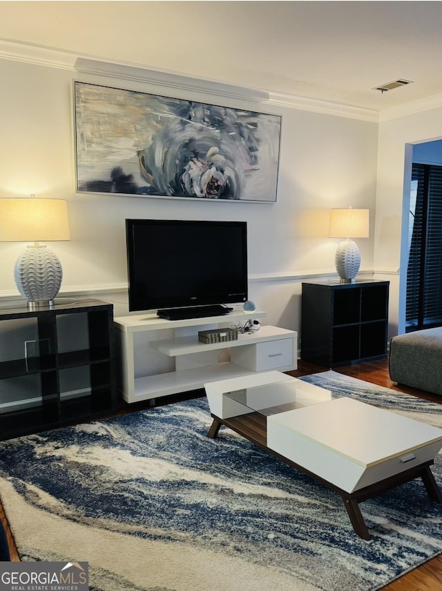 living area featuring ornamental molding, visible vents, and wood finished floors