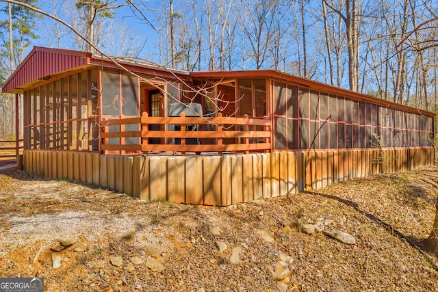 view of property exterior with board and batten siding and a sunroom