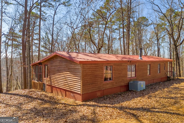 view of side of property featuring central air condition unit, crawl space, and metal roof