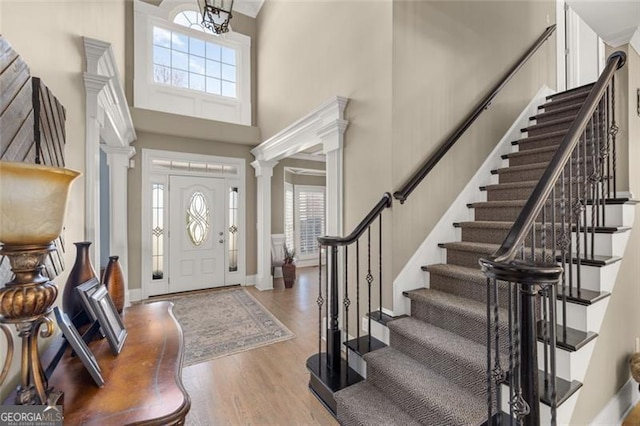 entrance foyer featuring ornate columns, plenty of natural light, a high ceiling, and wood finished floors