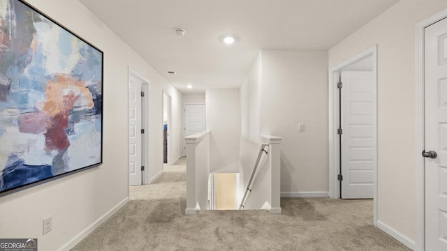 hallway featuring baseboards, recessed lighting, an upstairs landing, and light colored carpet