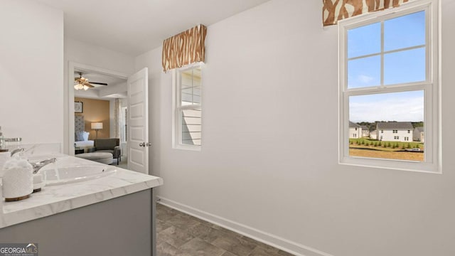 ensuite bathroom featuring ceiling fan, baseboards, connected bathroom, and vanity