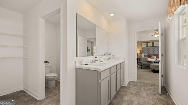 ensuite bathroom featuring toilet, vanity, baseboards, and ensuite bathroom