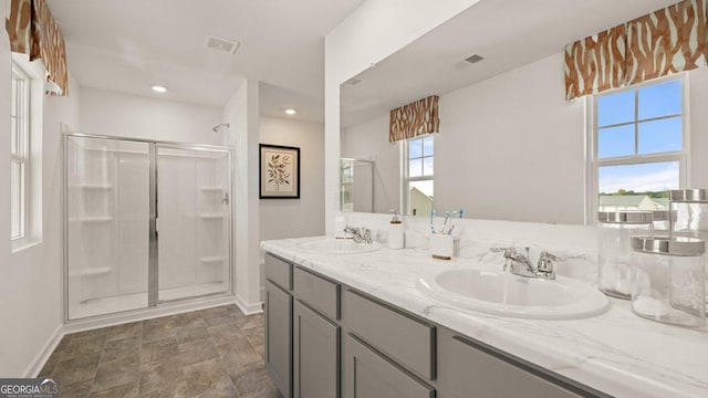 bathroom featuring double vanity, a stall shower, a sink, and visible vents