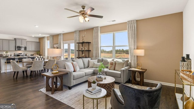 living area with dark wood-style floors, baseboards, visible vents, and ceiling fan