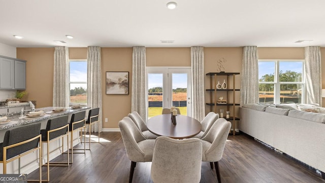 dining room featuring a healthy amount of sunlight, dark wood-style floors, visible vents, and baseboards