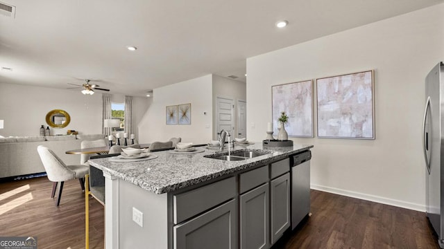 kitchen featuring dark wood-style flooring, stainless steel appliances, gray cabinets, open floor plan, and a sink