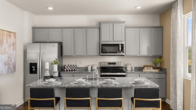 kitchen with appliances with stainless steel finishes, gray cabinets, and light stone counters