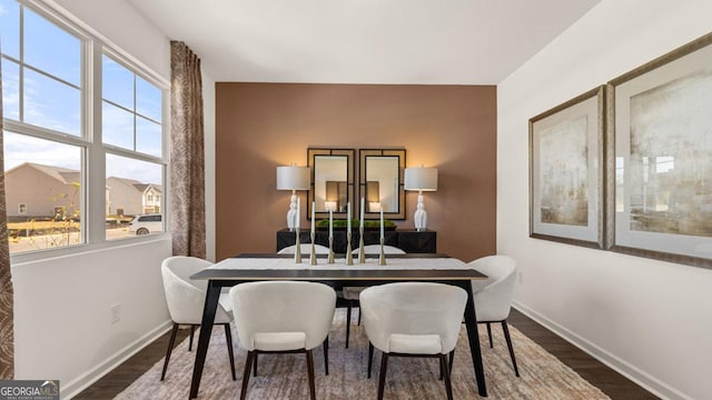 dining area with dark wood-type flooring and baseboards