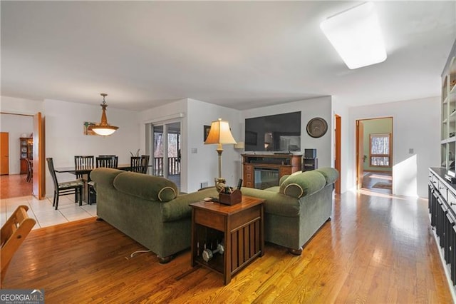 living room featuring a glass covered fireplace and light wood-style flooring