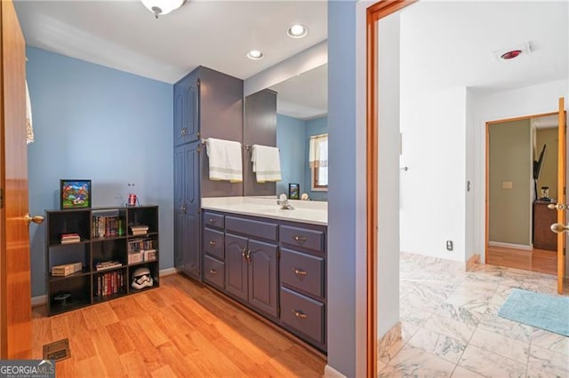 bathroom with baseboards, visible vents, wood finished floors, vanity, and recessed lighting