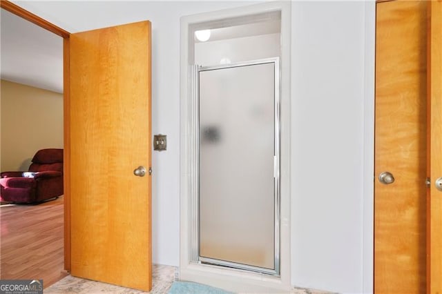 full bath featuring a shower stall and wood finished floors