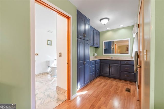 bathroom with baseboards, visible vents, wood finished floors, and vanity