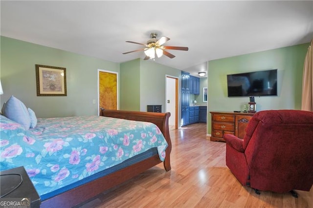 bedroom featuring light wood finished floors, a ceiling fan, and ensuite bathroom