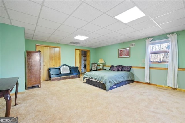 carpeted bedroom featuring a paneled ceiling, visible vents, and baseboards