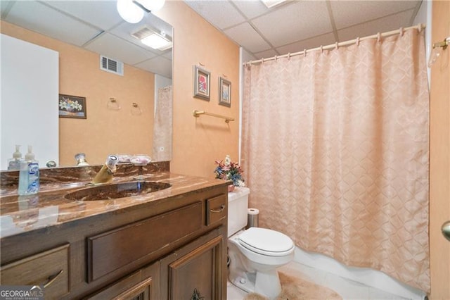 full bathroom with visible vents, toilet, vanity, a drop ceiling, and tile patterned floors